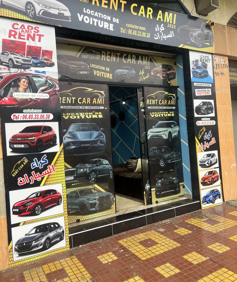 La devanture Rent Car Ami23 sur la Route de Tétouan, couverte de bannières or et noir